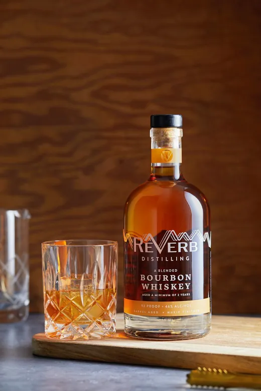ReVerb Bourbon in a crystal rocks glass beside the bottle